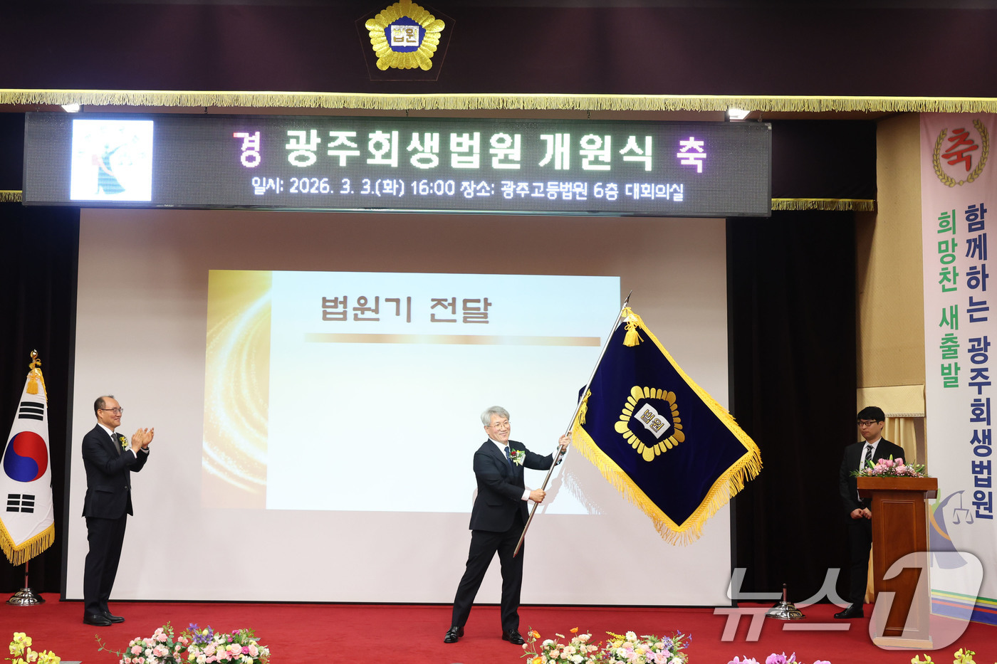 (광주=뉴스1) 이승현 기자 = 김성주 초대 광주회생법원장이 3일 오후 광주 동구 고등법원에서 열린 광주회생법원 개원식에서 전달받은 법원기를 흔들고 있다. 2026.3.3/뉴스1