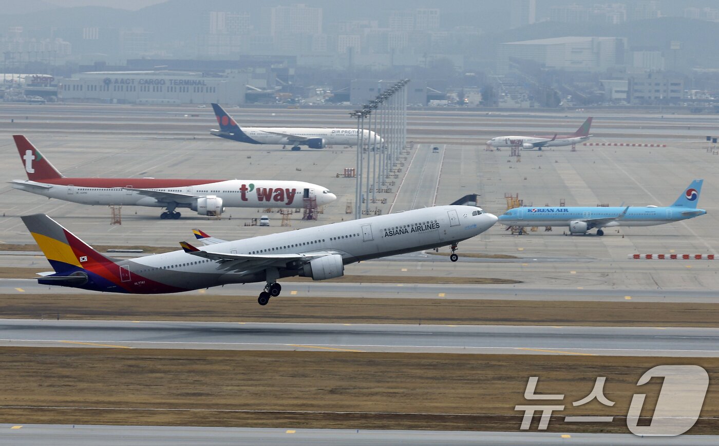 본문 이미지 - 인천국제공항 계류장에 대기하는 항공기 앞으로 아시아나항공 항공기가 이륙하고 있다. ⓒ 뉴스1 박정호 기자