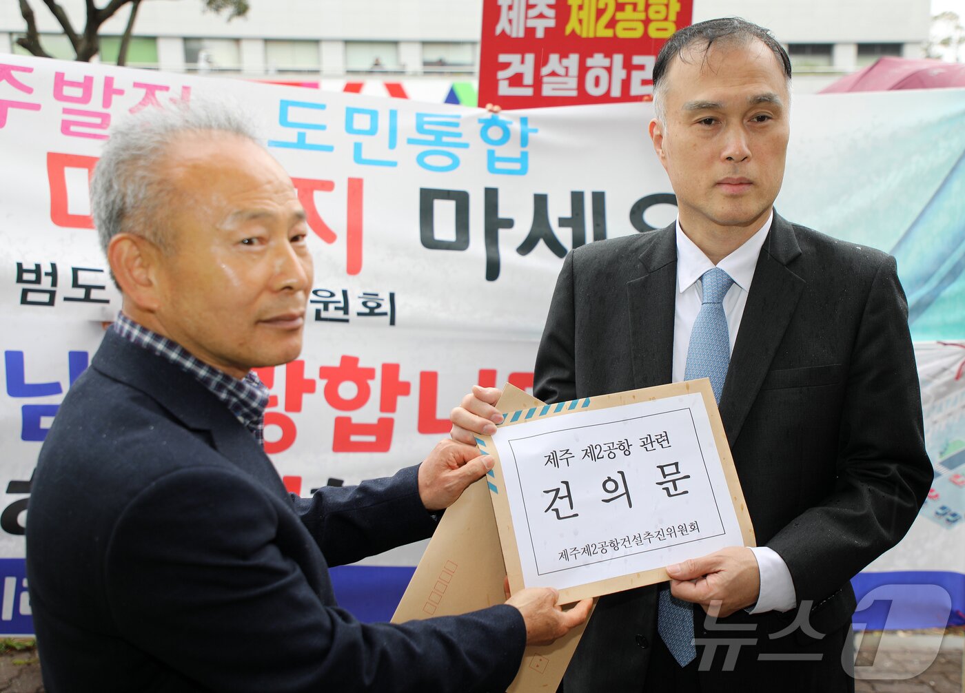 본문 이미지 - 30일 오후 이재명 대통령 주재 타운홀미팅이 열리는 제주시 한라컨벤션센터 앞에서 제주 제2공항 건설사업  찬성 단체 관계자가 대통령 직속 지방시대위원회 관계자에게 건의문을 전달하고 있다. 2026.3.30 ⓒ 뉴스1 오미란 기자