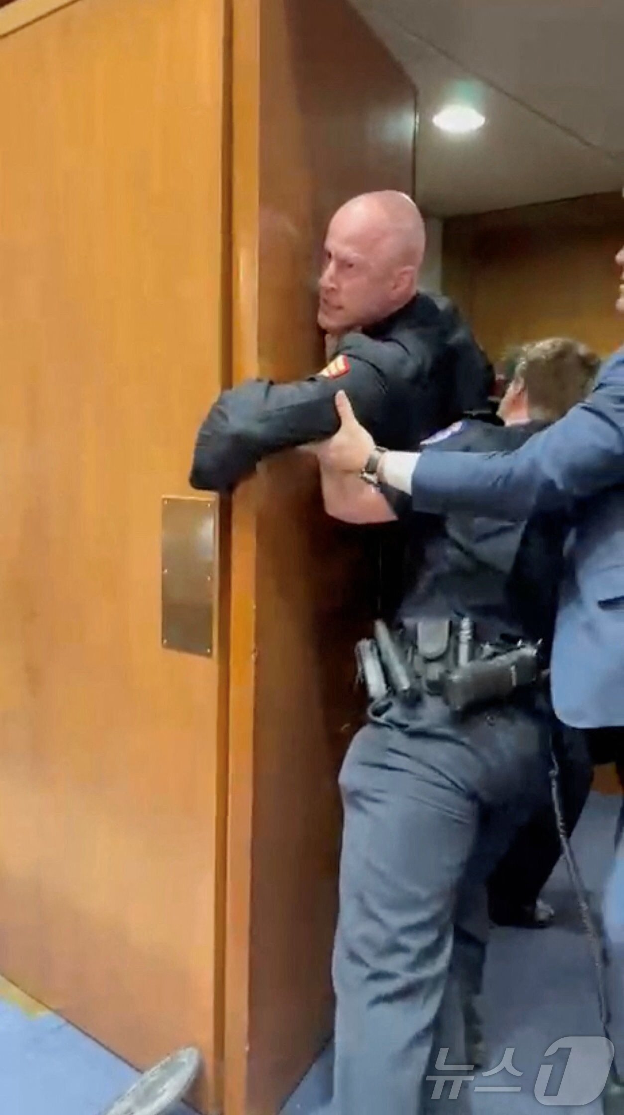 본문 이미지 - 미 녹색당 노스캐롤라이나주 상원의원으로 출마한 전직 미 해병 브라이언 맥기니스(44)가 지난 3일(현지시간) 상원 군사위원회 산하 소위원회 청문회에서 "아무도 이스라엘을 위해 싸우고 싶어 하지 않는다＂고 외치던 중 끌려 나가고 있다. 2026.03.03. ⓒ 로이터=뉴스1