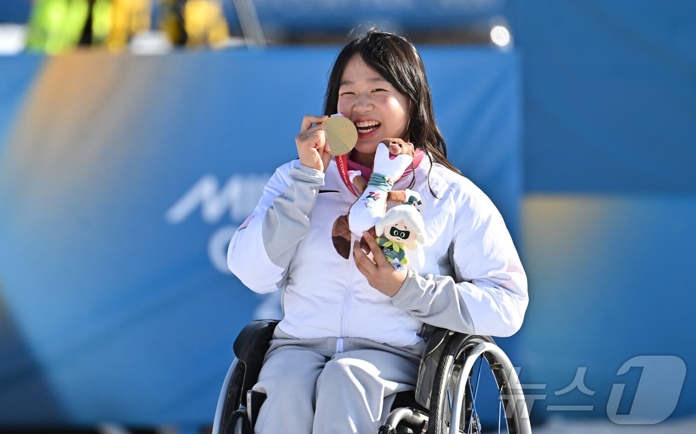 본문 이미지 - 바이애슬론 김윤지가 8일(현지시간) 이탈리아 테세로 크로스컨트리 스키 스타디움에서 열린 2026 밀라노 코르티나 동계패럴림픽 바이애슬론 12.5km 시상식에서 금메달을 깨물고 있다. 2026.3.9 ⓒ 뉴스1 사진공동취재단