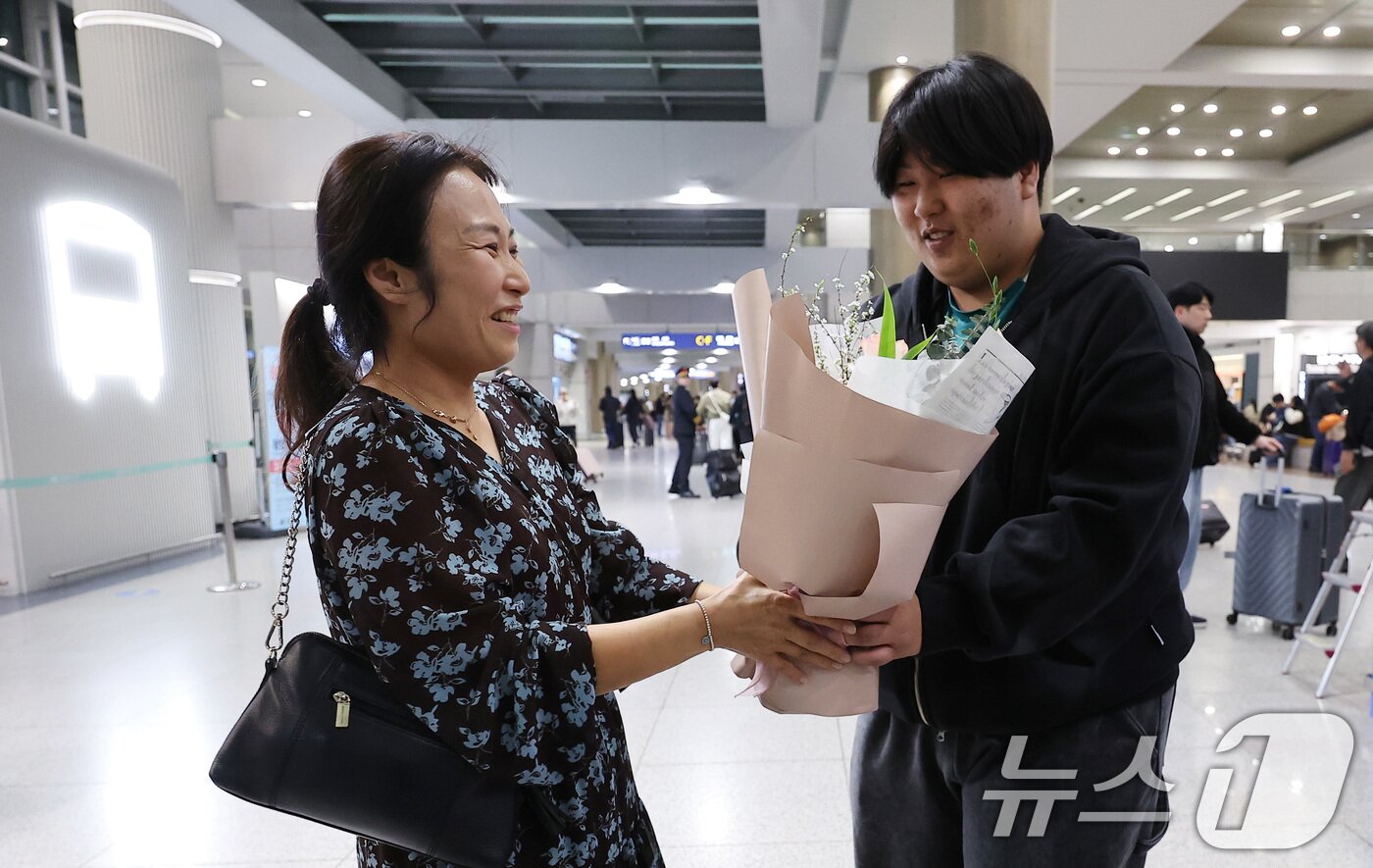 본문 이미지 - '중동 상황' 장기화로 인해 정부에서 추진한 전세기를 타고 아랍에미리트(UAE)에서 출발해 9일 새벽 인천국제공항을 통해 귀국한 한 승객이 아들로부터 꽃다발을 받고 있다. 2026.3.9 ⓒ 뉴스1 김성진 기자