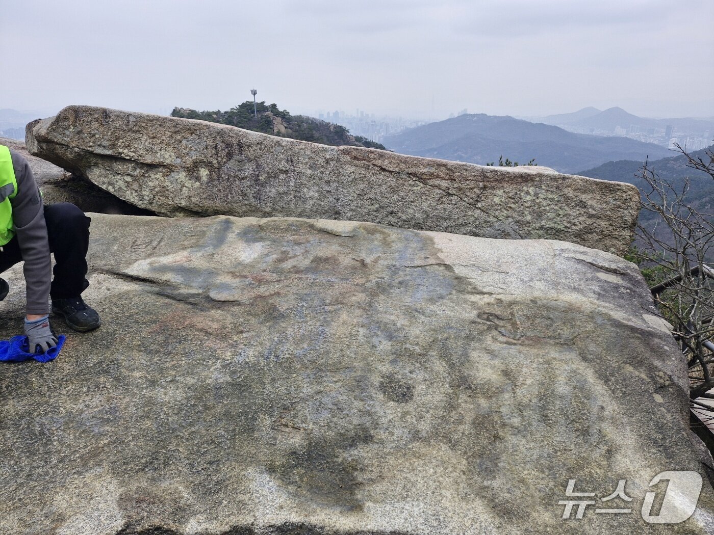 본문 이미지 - 래커 낙서로 인해 훼손된 관악산 마당바위를 복원 중인 모습. (사진. 관악구청 제공)
