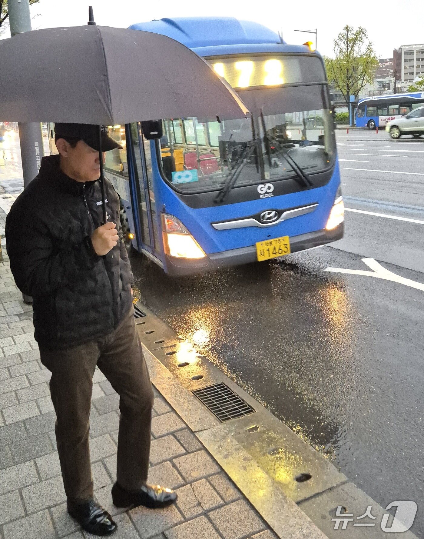 본문 이미지 - 오세훈 서울시장이 순천향대병원 정류장에서 우산을 쓰고 472번 버스를 기다리고 있다.