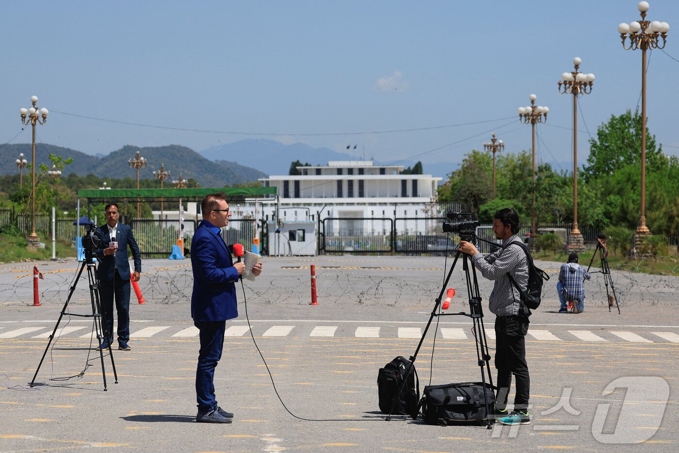 본문 이미지 - 미국·이란 간 평화회담을 하루 앞둔 10일(현지시간) 파키스탄 이슬라마바드에서 취재진이 대통령 관저를 배경으로 취재하고 있다. 2026.04.10. ⓒ 로이터=뉴스1