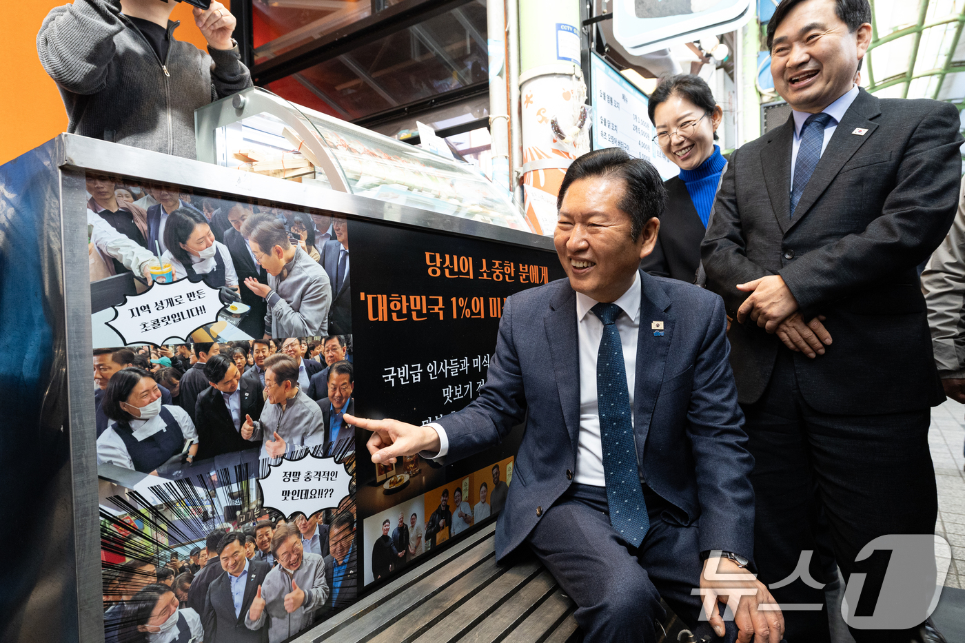 (속초=뉴스1) 이승배 기자 = 정청래 더불어민주당 대표가 12일 강원 속초관광수산시장을 찾아 가게에 붙어 있는 이재명 대통령의 예전 사진을 살펴보고 있다. 2026.4.12/뉴스 …