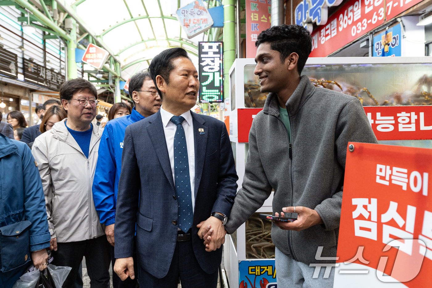 (속초=뉴스1) 이승배 기자 = 정청래 더불어민주당 대표가 12일 강원 속초관광수산시장을 찾아 외국인 가게 직원과 대화하고 있다. 2026.4.12/뉴스1