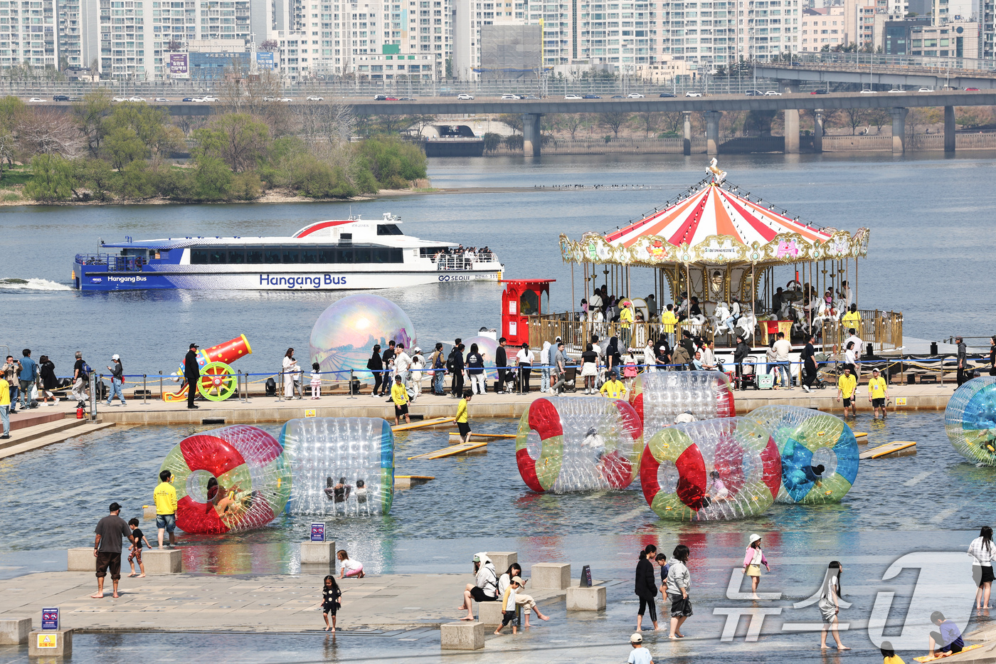 (서울=뉴스1) 임지훈 인턴기자 = 12일 오후 서울 여의도 한강공원 물빛광장에서 열린 '서울스프링페스티벌'을 찾은 시민들이 워터볼 굴리기와 회전목마를 체험하고 있다.‘2026 서 …