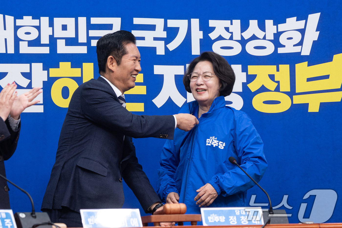 (서울=뉴스1) 이승배 기자 = 정청래 더불어민주당 대표가 13일 서울 여의도 국회에서 열린 경기도지사 후보 환영식에서 추미애 후보에게 당 점퍼를 입혀주고 있다. 2026.4.13 …