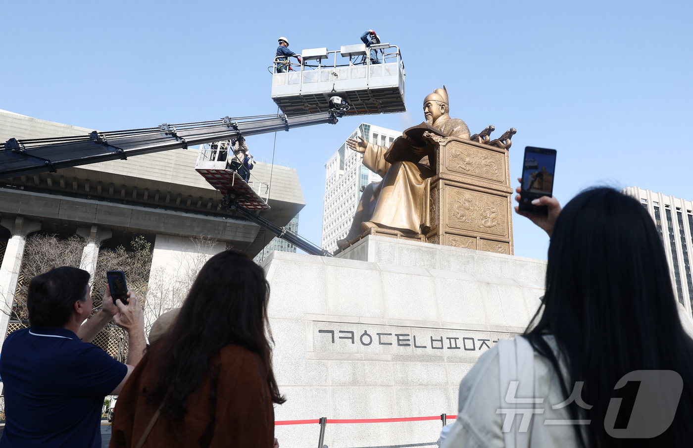 (서울=뉴스1) 김민지 기자 = 13일 오전 서울 종로구 세종로 광화문광장에서 세종대왕 동상을 세척 작업이 진행중인 가운데 외국인 관광객들이 이 모습을 지켜보고 있다. 2026.4 …