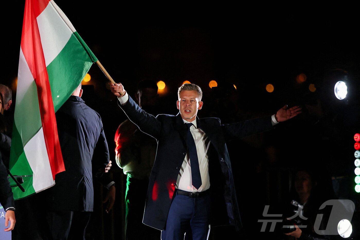 본문 이미지 - 12일(현지시간) 헝가리 총선에서 승리한 야당 티서당의 당수인 페테르 마자르가 부다페스트에서 헝가리 국기를 흔들고 있다. 2026.04.12 ⓒ 로이터=뉴스1