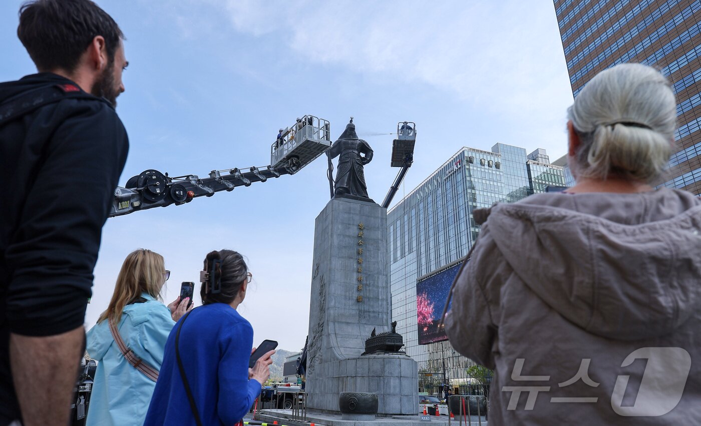 본문 이미지 - 서울시 관계자들이 14일 서울 종로구 광화문광장에서 이순신 장군 동상을 세척 작업이 진행되는 가운데 외국인 관광객들이 이 모습을 지켜보고 있다. 2026.4.14 ⓒ 뉴스1 김성진 기자