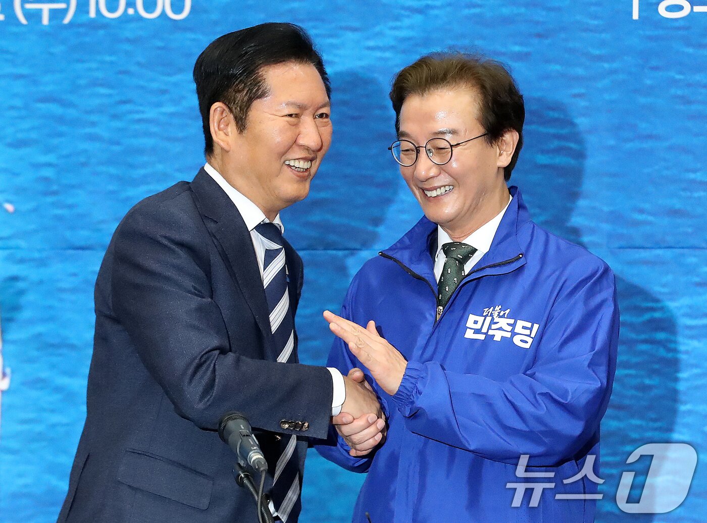 본문 이미지 - 정청래 더불어민주당 대표가 15일 부산 동구 부산항국제전시컨벤션센터에서 열린 부산 현장 최고위원회의에서 전재수 부산시장 후보에게 당 점퍼를 입혀준 뒤 악수하고 있다. 2026.4.15 ⓒ 뉴스1 윤일지 기자