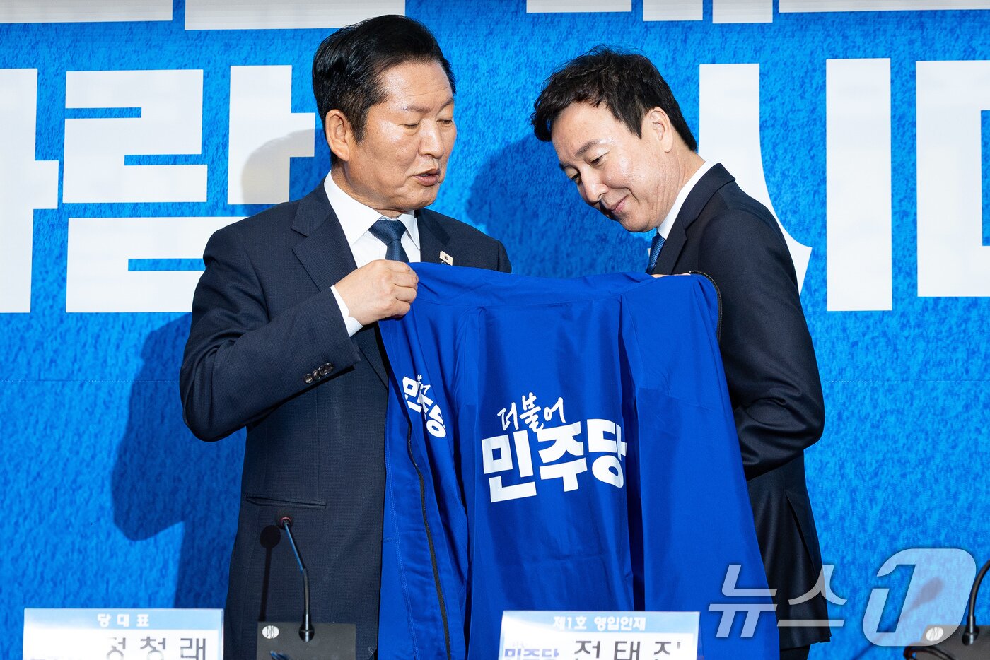 본문 이미지 - 정청래 더불어민주당 대표가 17일 서울 여의도 국회에서 열린 제1차 인재영입식에서 전태진 변호사에게 당 점퍼를 입혀주고 있다.  2026.4.17 ⓒ 뉴스1 유승관 기자