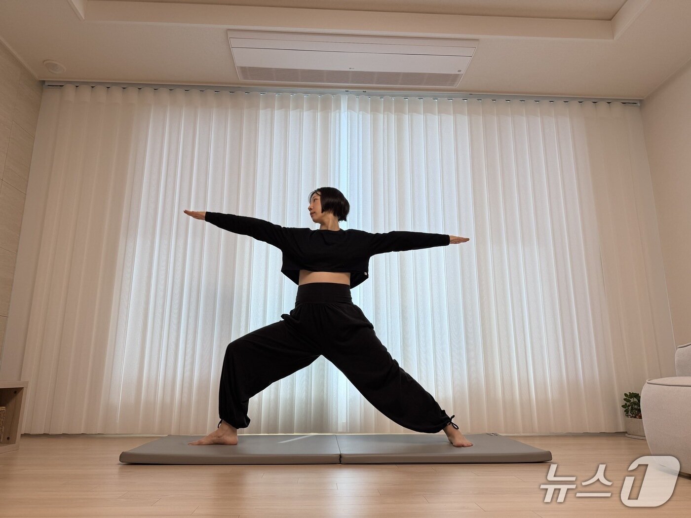 본문 이미지 - 김유빈 요가강사가 임신부에 좋은 전사자세2를 보여주고 있다. 다리를 약 120cm로 넓게 벌린 후 한쪽 발을 90도 바깥으로 틀고 그 방향으로 무릎을 열어 골반을 연다. 양팔을 옆으로 수평으로 벌리고 시선은 구부린 무릎 쪽 손끝을 향한다. 치골, 배꼽, 가슴 중앙, 미간이 같은 선상에 있도록 정렬하고 고개만 돌린다. 하체 근력과 골반·척추의 안정성, 유연성 향상에 도움을 준다.ⓒ 뉴스1 서장원 기자