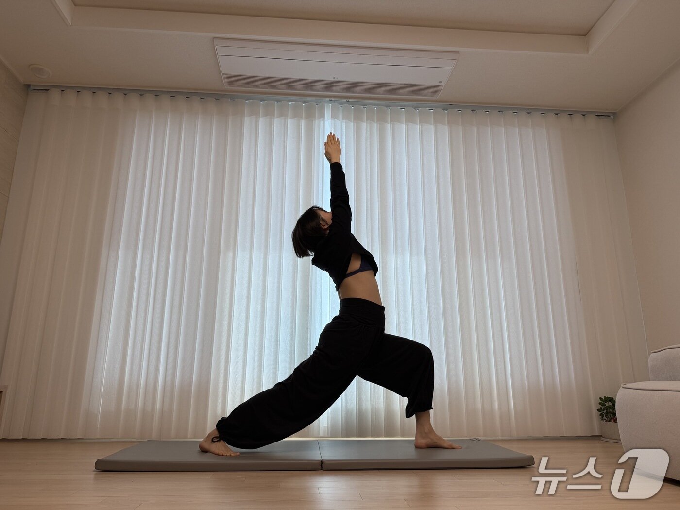 본문 이미지 - 김유빈 요가강사가 전사자세1을 보여주고 있다. 한쪽 다리를 앞으로 내딛어 런지 형태로 서고, 팔을 위로 뻗어 상체를 뒤로 젖히는 요가 기본자세다. 하체 근력과 안정성, 코어 지지력, 골반·척추 정렬 인식, 흉곽 확장 및 호흡 질 개선에 도움이 된다.ⓒ 뉴스1 서장원 기자