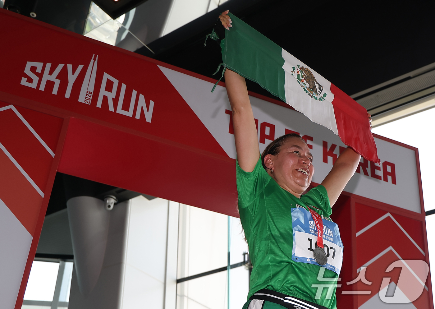 (서울=뉴스1) 황기선 기자 = 19일 서울 송파구 롯데월드타워에서 열린 수직 마라톤 대회 '2026 롯데월드타워 스카이런' 행사에서 한 참가자가 멕시코 국기를 들고 기념 촬영을 …