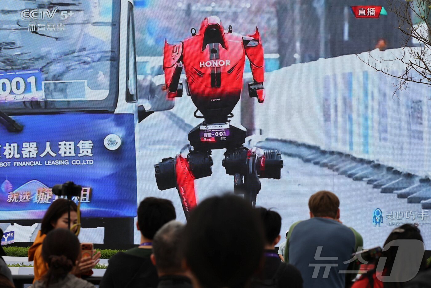 본문 이미지 - 19일 중국 베이징에서 열린 제2회 베이징 이타운 하프 마라톤 및 휴머노이드 로봇 하프 마라톤에서 시민들이 휴머노이드 로봇이 달리는 모습을 시청하고 있다. ⓒ 로이터=뉴스1ⓒ 로이터=뉴스1