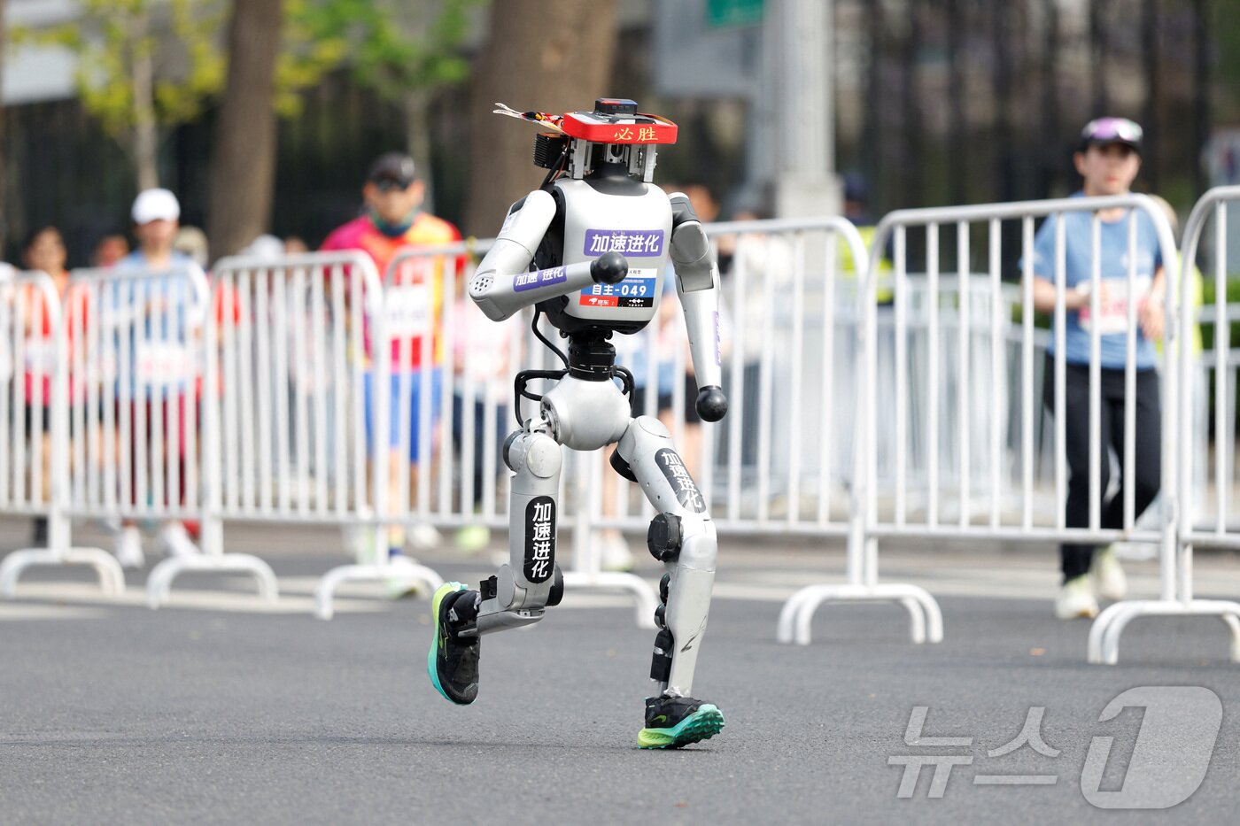본문 이미지 - 19일 중국 베이징에서 열린 제2회 베이징 이타운 하프 마라톤 및 휴머노이드 로봇 하프 마라톤에서 휴머노이드 로봇이 달리고 있다. ⓒ 로이터=뉴스1