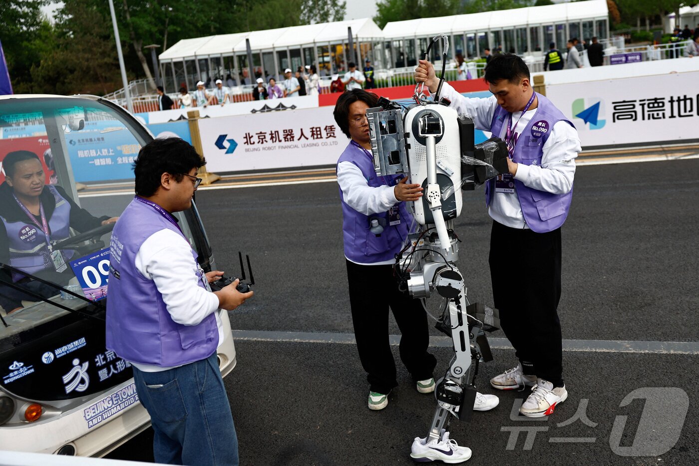 본문 이미지 - 19일 중국 베이징에서 열린 제2회 베이징 이타운 하프 마라톤 및 휴머노이드 로봇 하프 마라톤에서 팀원들이 넘어진 휴머노이드 로봇을 점검하고 있다. ⓒ 로이터=뉴스1