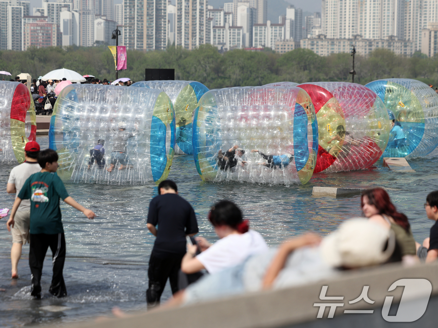 (서울=뉴스1) 황기선 기자 = 낮 기온이 전국 내륙을 중심으로 최고 29도로 치솟으며 초여름 날씨를 보인 19일 오후 서울 영등포구 여의도 한강공원 물빛광장에서 시민들이 워터볼 …