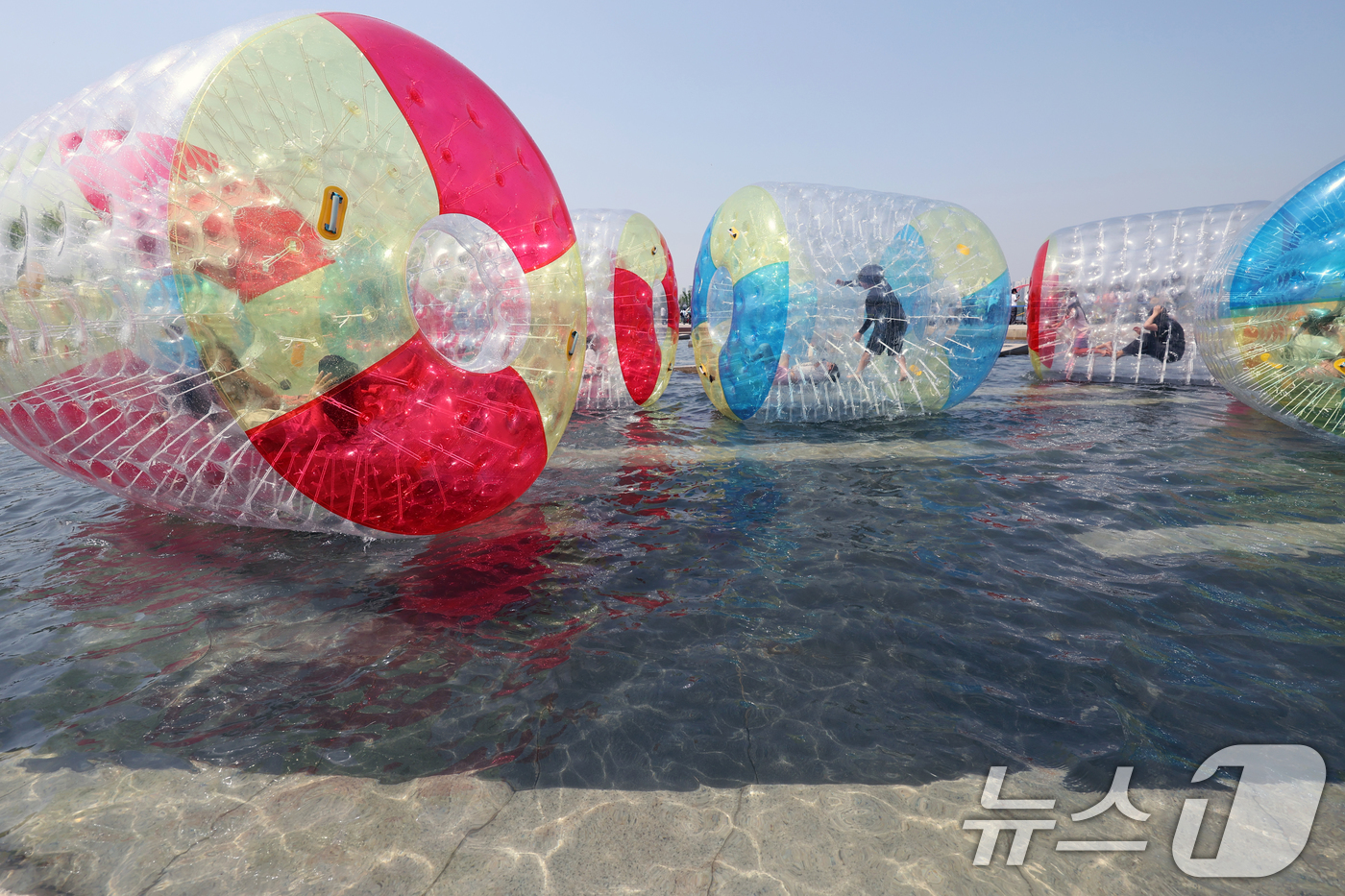 (서울=뉴스1) 황기선 기자 = 낮 기온이 전국 내륙을 중심으로 최고 29도로 치솟으며 초여름 날씨를 보인 19일 오후 서울 영등포구 여의도 한강공원 물빛광장에서 시민들이 워터볼 …