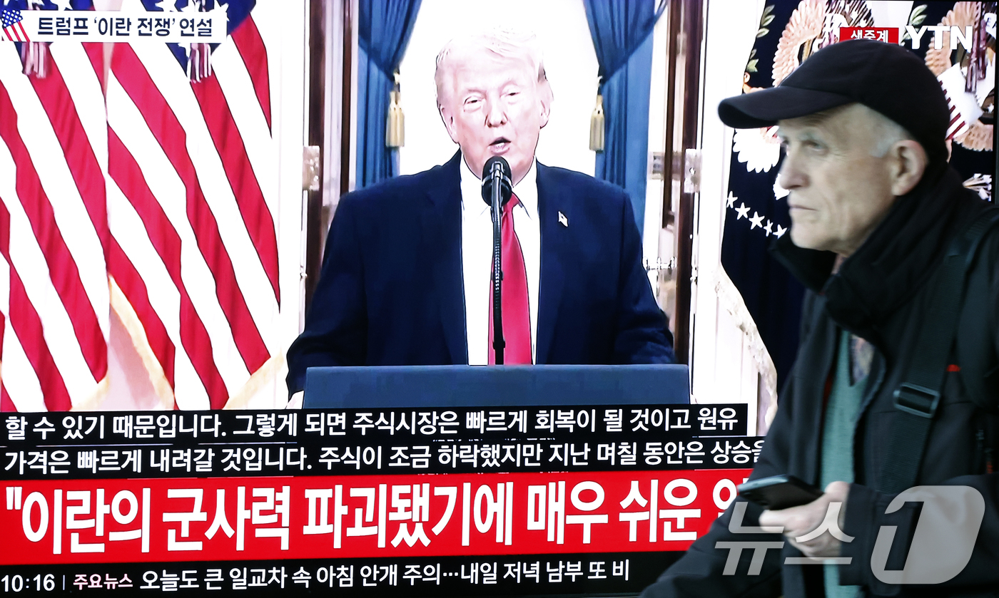 (서울=뉴스1) 박정호 기자 = 2일 오전 서울시 용산구 서울역 대합실에서 한 외국인 관광객이 도널드 트럼프 미국 대통령의 이란 전쟁 상황 관련 대국민 연설 TV 생중계 앞을 지나 …