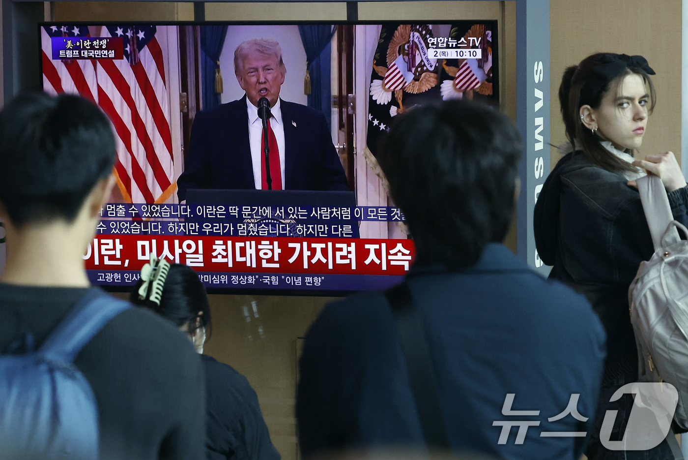 (서울=뉴스1) 박정호 기자 = 2일 오전 서울시 용산구 서울역 대합실에서 시민들이 도널드 트럼프 미국 대통령의 이란 전쟁 상황 관련 대국민 연설 TV 생중계를 지켜보고 있다. …