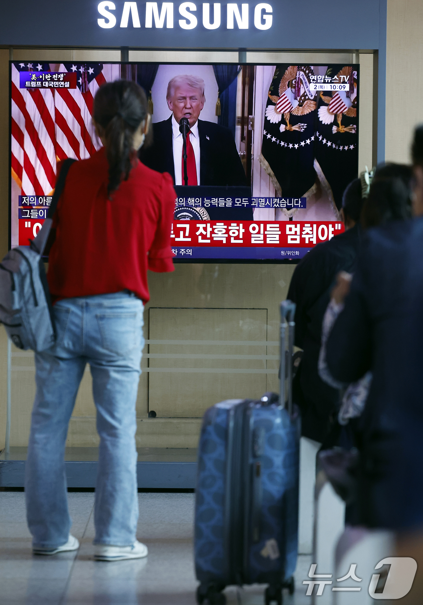 (서울=뉴스1) 박정호 기자 = 2일 오전 서울시 용산구 서울역 대합실에서 시민들이 도널드 트럼프 미국 대통령의 이란 전쟁 상황 관련 대국민 연설 TV 생중계를 지켜보고 있다. …