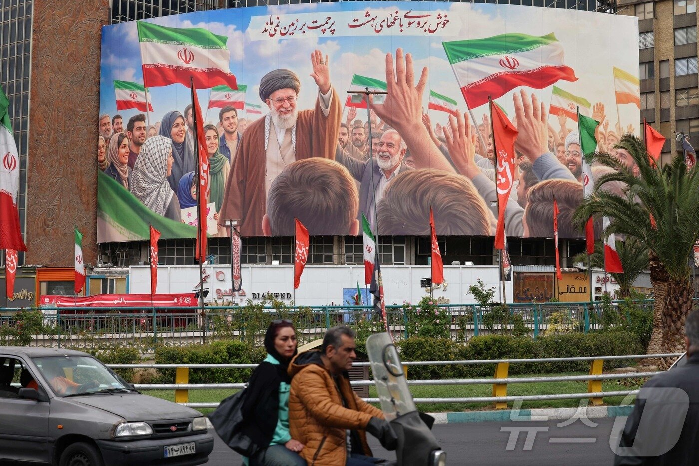 본문 이미지 - 이란 테헤란 발리아스르 광장에서 19일(현지시간) 촬영된 사진. 차량들이 사망한 이란 최고지도자 아야톨라 알리 하메네이의 대형 옥외 광고판을 지나가고 있다. 2026.04.19 ⓒ AFP=뉴스1