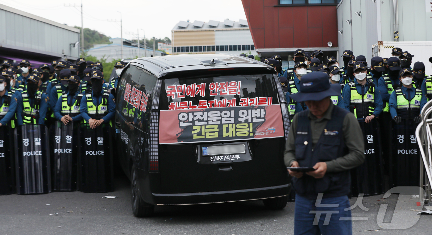 (진주=뉴스1) 윤일지 기자 = 20일 경남 진주시 정촌면 CU 진주물류센터 앞에서 경찰이 민주노총 화물연대 CU지회 노조원들을 막아 서고 있다. 물류센터 정문 앞에는 진입을 시도 …