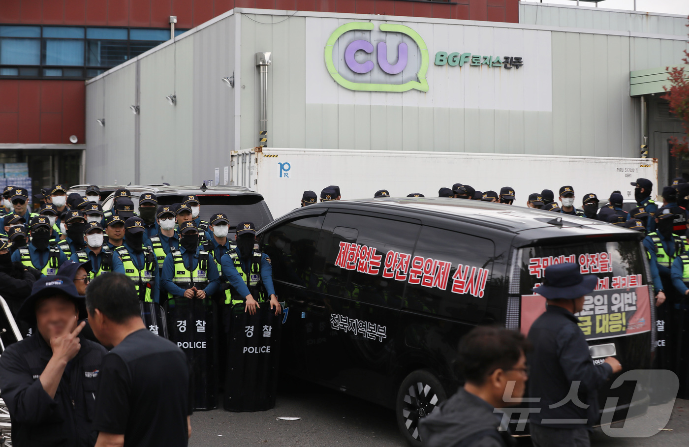 (진주=뉴스1) 윤일지 기자 = 20일 경남 진주시 정촌면 CU 진주물류센터 앞에서 경찰이 민주노총 화물연대 CU지회 노조원들을 막아 서고 있다. 물류센터 정문 앞에는 진입을 시도 …