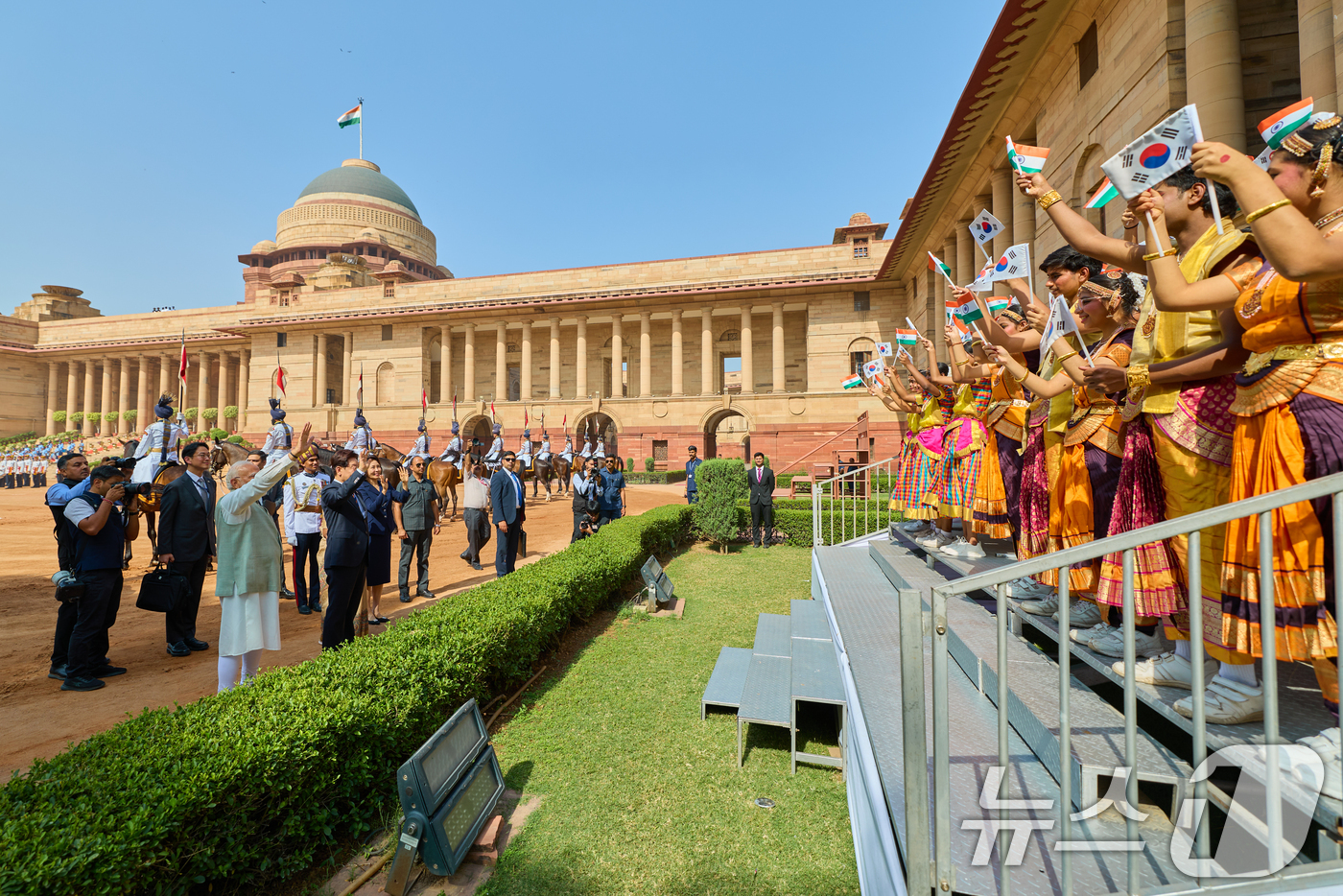 (뉴델리(인도)=뉴스1) 이재명 기자 = 이재명 대통령과 김혜경 여사가 20일 뉴델리 대통령궁 광장에서 열린 공식환영식에서 환영객들을 향해 손을 흔들고 있다. (공동취재) 2026 …
