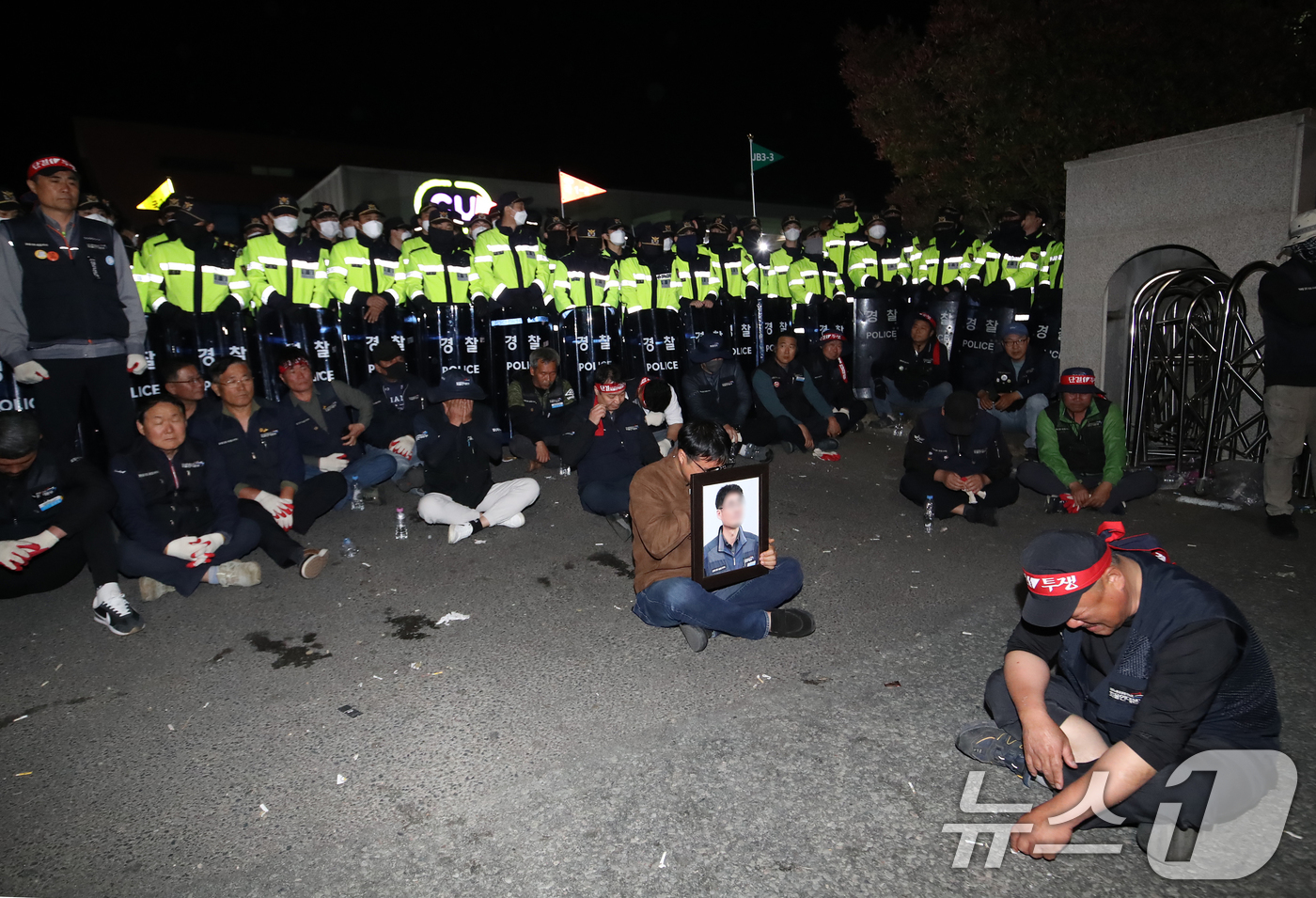 (진주=뉴스1) 윤일지 기자 = 20일 경남 진주시 정촌면 CU 진주물류센터 앞에서 화물연대 노조원이 집회 중 2.5톤 화물차에 치어 숨진 노조원의 영정을 들고 슬픔에 잠겨 있다. …
