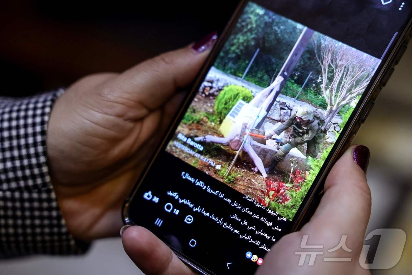 (베이루트 AFP=뉴스1) 윤다정 기자 = 20일(현지시간) 레바논 베이루트에서 한 여성이 소셜미디어 게시물을 확인하고 있다. 게시물 속 사진에는 이스라엘군 병사가 십자가에서 떨어 …