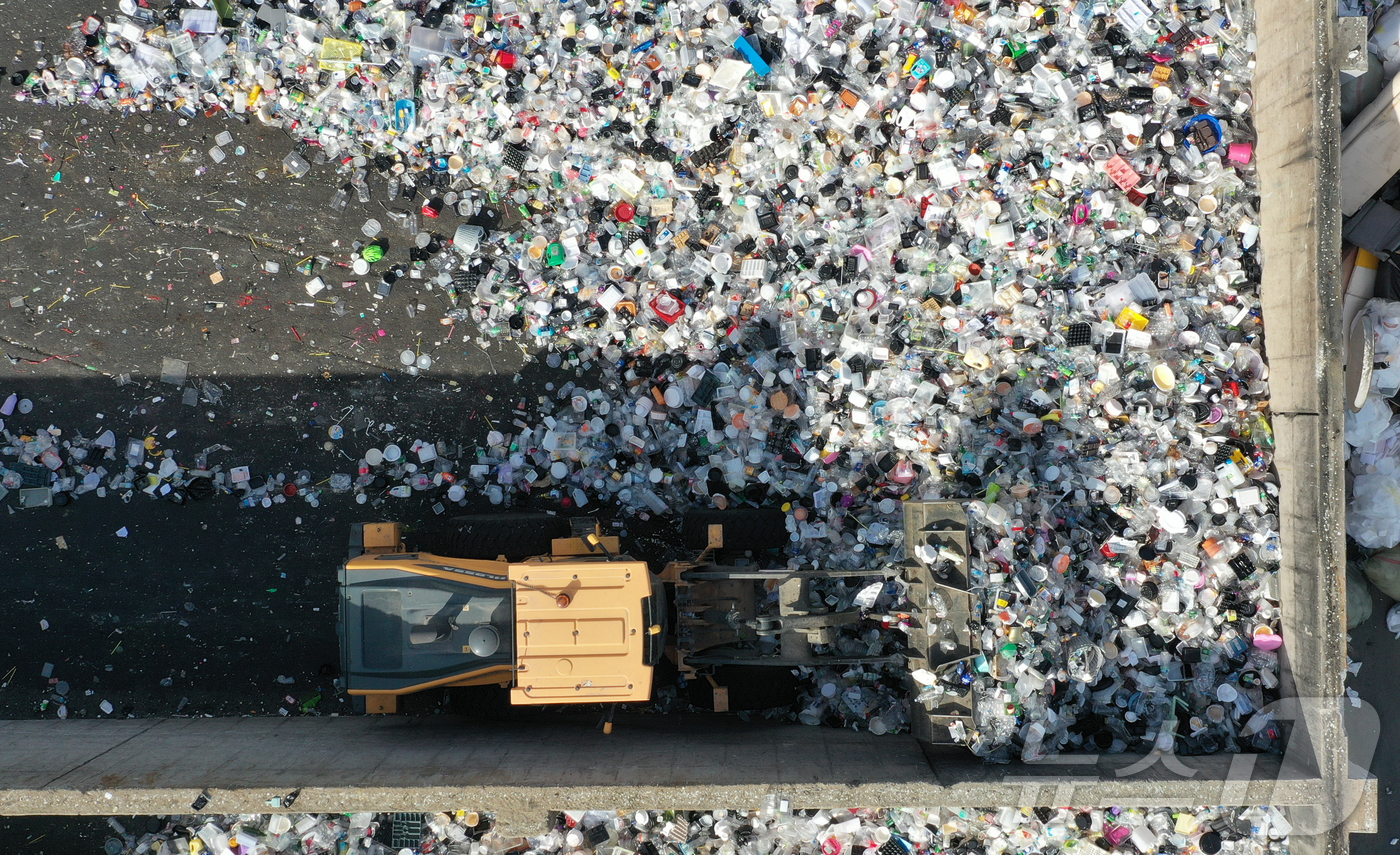 (수원=뉴스1) 김영운 기자 = '지구의 날'을 하루 앞둔 21일 경기 수원시 영통구 수원시자원순환센터에서 관계자들이 재활용 쓰레기를 처리하고 있다.