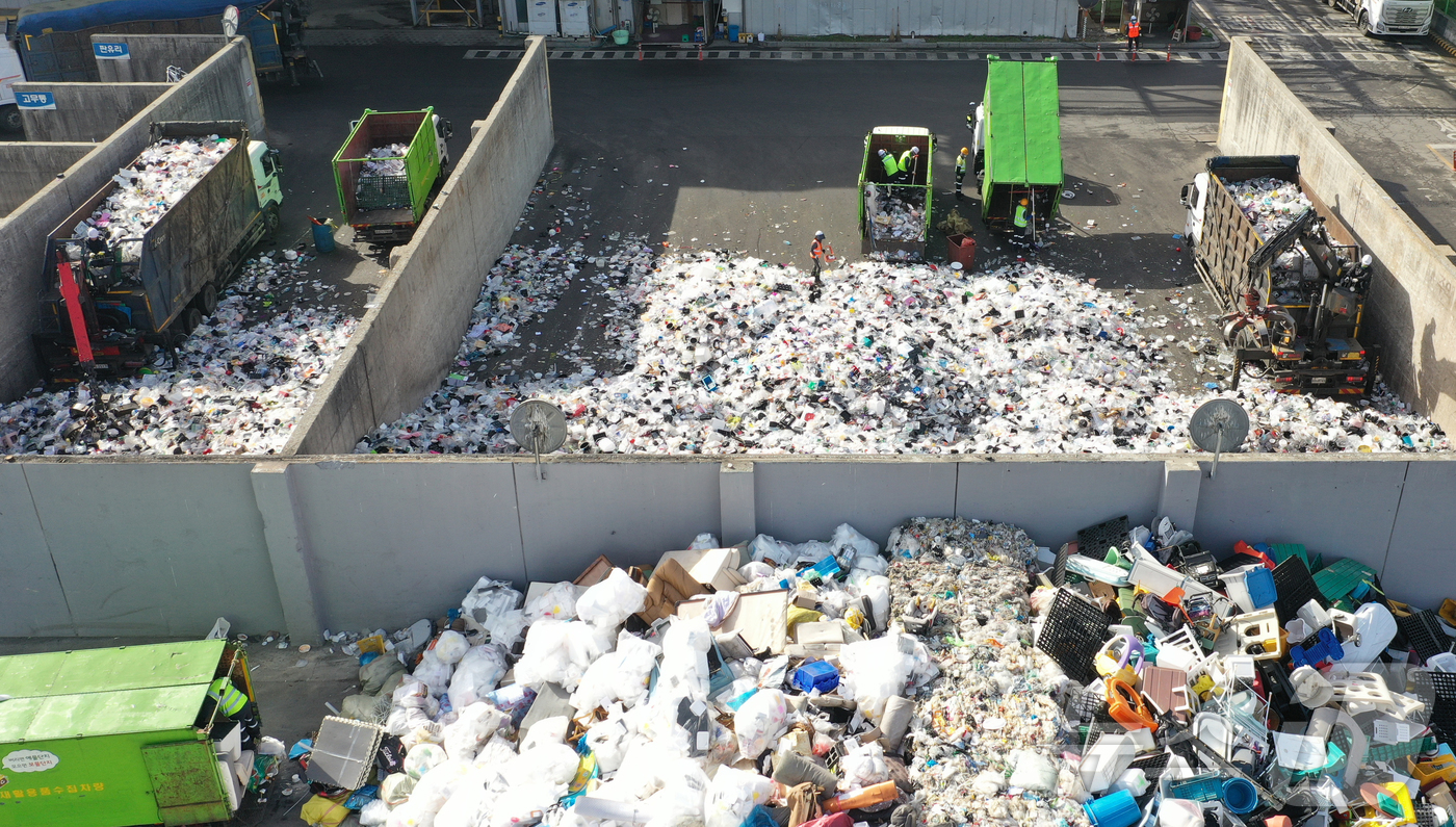 (수원=뉴스1) 김영운 기자 = '지구의 날'을 하루 앞둔 21일 경기 수원시 영통구 수원시자원순환센터에서 관계자들이 재활용 쓰레기를 처리하고 있다.