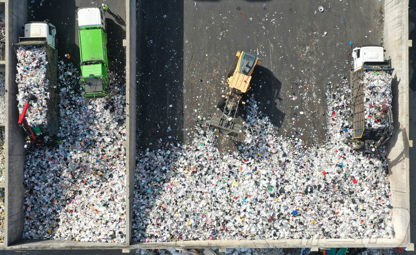 (수원=뉴스1) 김영운 기자 = '지구의 날'을 하루 앞둔 21일 경기 수원시 영통구 수원시자원순환센터에서 관계자들이 재활용 쓰레기를 처리하고 있다.
