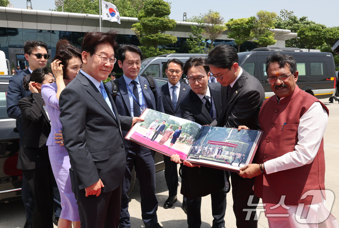 (뉴델리(인도)=뉴스1) 이재명 기자 = 인도 국빈 방문을 마친 이재명 대통령과 김혜경 여사가 21일(현지시간) 뉴델리 팔람 군비행장에서 베트남행 공군 1호기 탑승 전 사진첩을 선 …