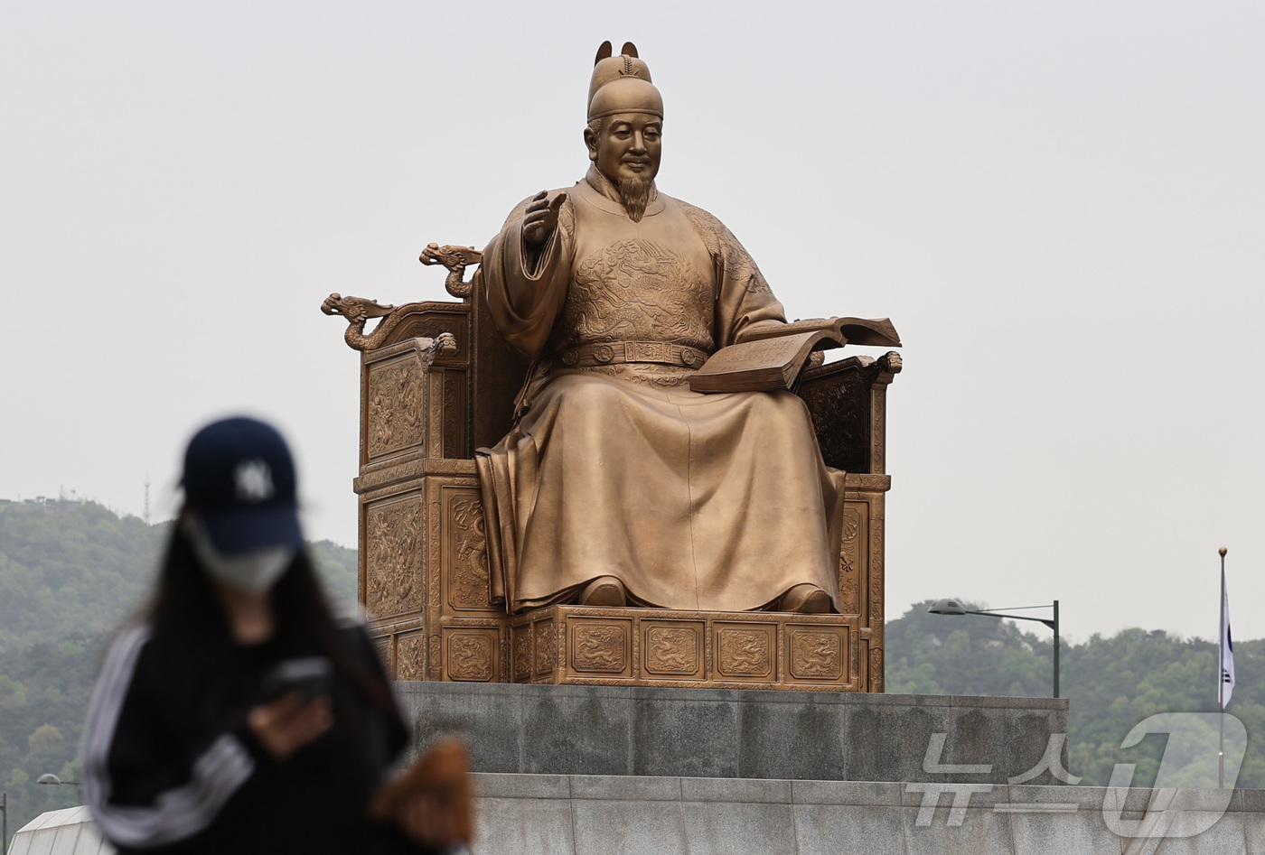 (서울=뉴스1) 이종수 인턴기자 = 잔존 황사의 영향으로 미세먼지가 ‘나쁨’ 수준을 보인 22일 오전 서울 종로구 광화문광장에서 시민이 마스크를 착용한 채 이동하고 있다. 2026 …