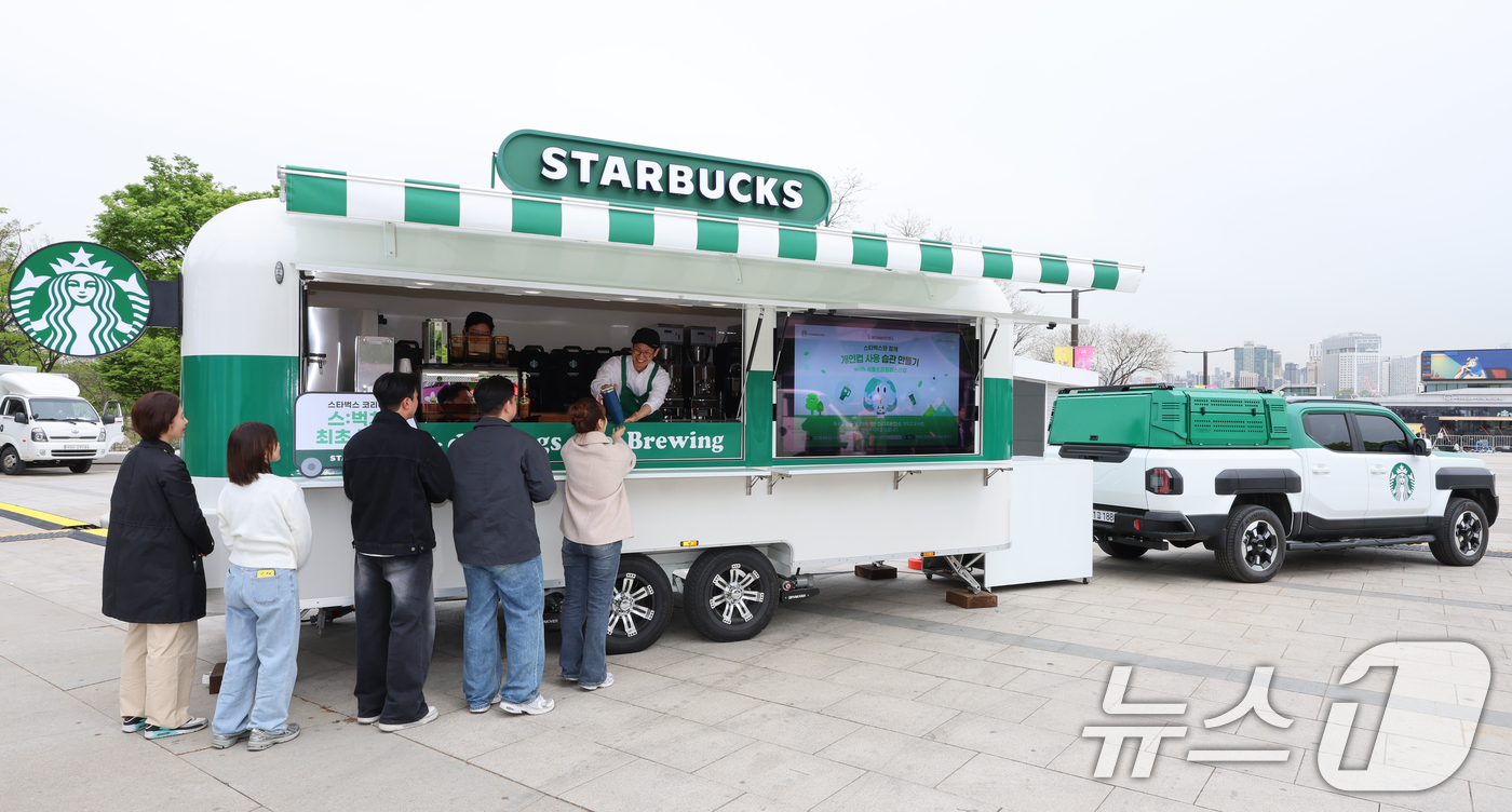 (서울=뉴스1) 안은나 기자 = 스타벅스 코리아가 지구의 날을 맞아 이동형 커피 트레일러 '스:벅차'를 공개한 22일 서울 여의도 한강공원에서 모델들이 개인 컵 지참 고객에게 선착 …