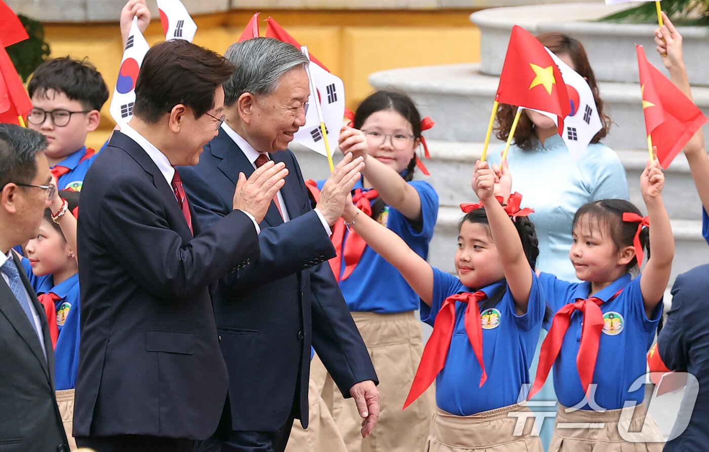 본문 이미지 - 이재명 대통령과 또 럼 베트남 당서기장이 22일(현지시간) 하노이 주석궁 대정원에서 열린 국빈 방문 공식환영식에서 환영객들을 향해 손인사하고 있다. 2026.4.22 ⓒ 뉴스1 이재명 기자