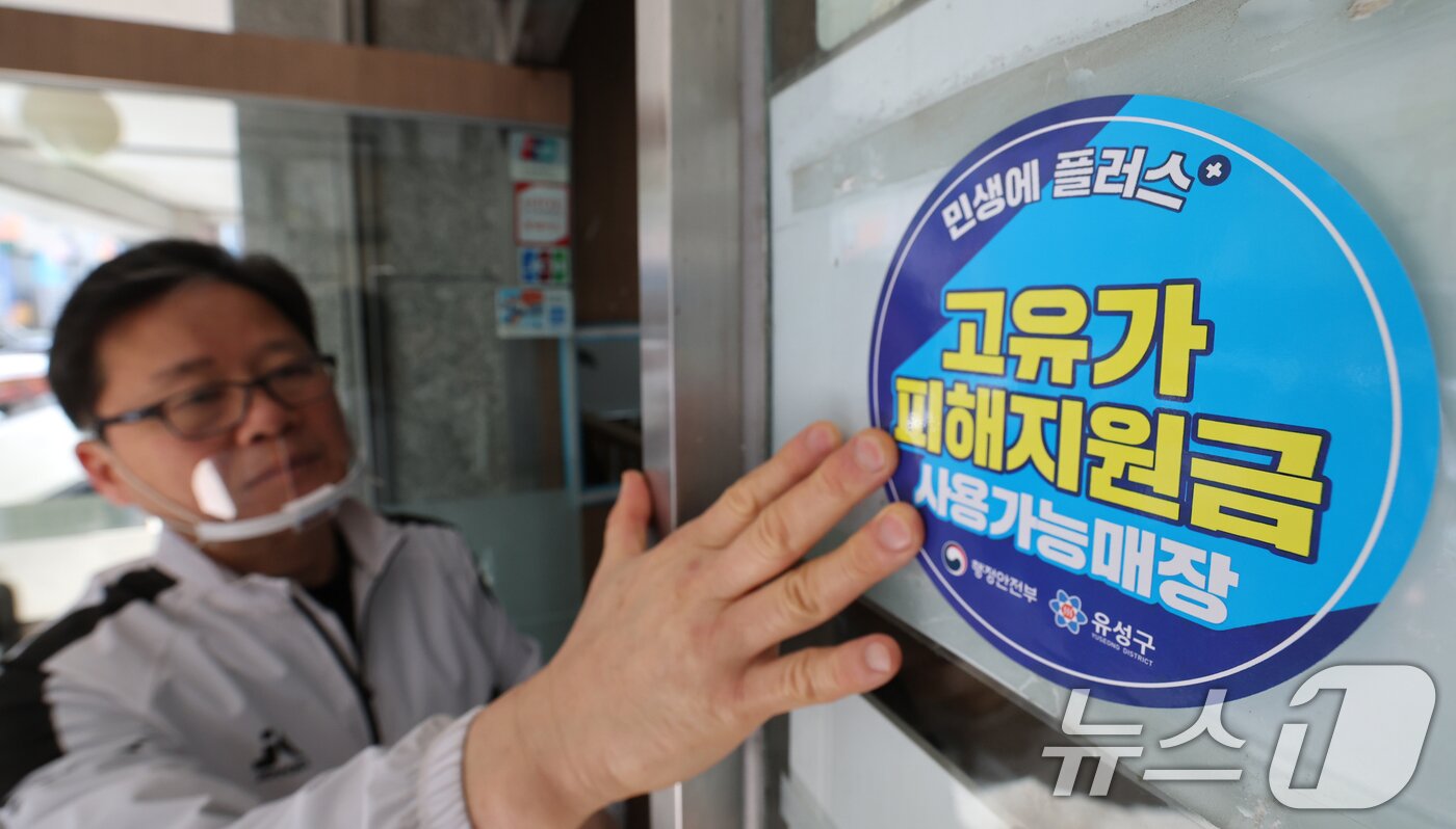 본문 이미지 - 고유가 피해지원금 신청을 앞두고 23일 대전 유성구 한 식당 주인이 피해지원금 사용가능매장 안내문을 붙이고 있다. 2026.4.23 ⓒ 뉴스1 김기태 기자