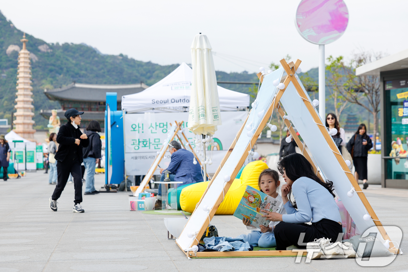 (서울=뉴스1) 안은나 기자 = 서울야외도서관 운영이 시작된 23일 오후 서울 종로구 광화문광장에 마련된 '광화문 책마당'에서 어린이가 어머니와 책을 읽고 있다. 2026.4.23 …