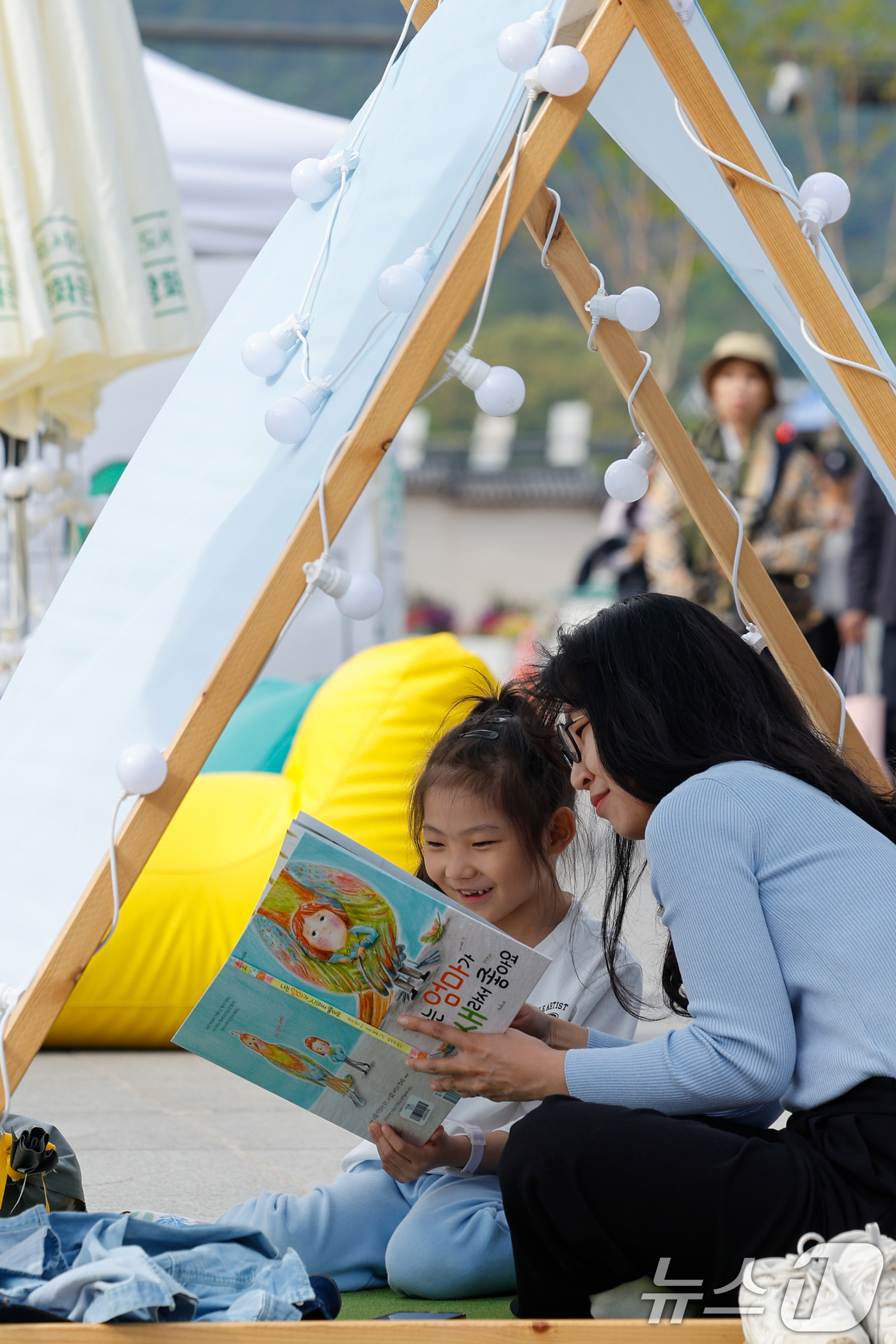(서울=뉴스1) 안은나 기자 = 서울야외도서관 운영이 시작된 23일 오후 서울 종로구 광화문광장에 마련된 '광화문 책마당'에서 어린이가 어머니와 책을 읽고 있다. 2026.4.23 …