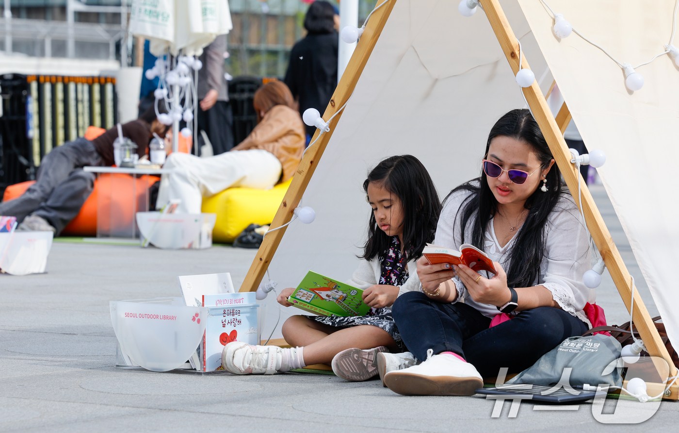 (서울=뉴스1) 안은나 기자 = 서울야외도서관 운영이 시작된 23일 오후 서울 종로구 광화문광장에 마련된 '광화문 책마당'에서 외국인 관광객들이 책을 읽고 있다. 2026.4.23 …