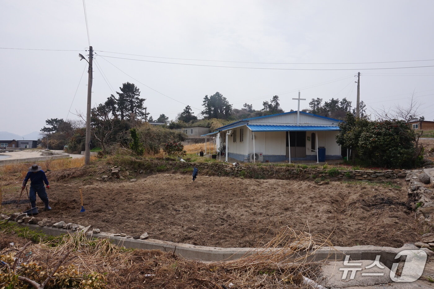 본문 이미지 - 백사장 앞 텃밭을 일궈 땅콩 심는 농부와 조립식 건물의 저도밀알교회. 2026.4.24. 뉴스1 ⓒ News1 조영석 기자 
