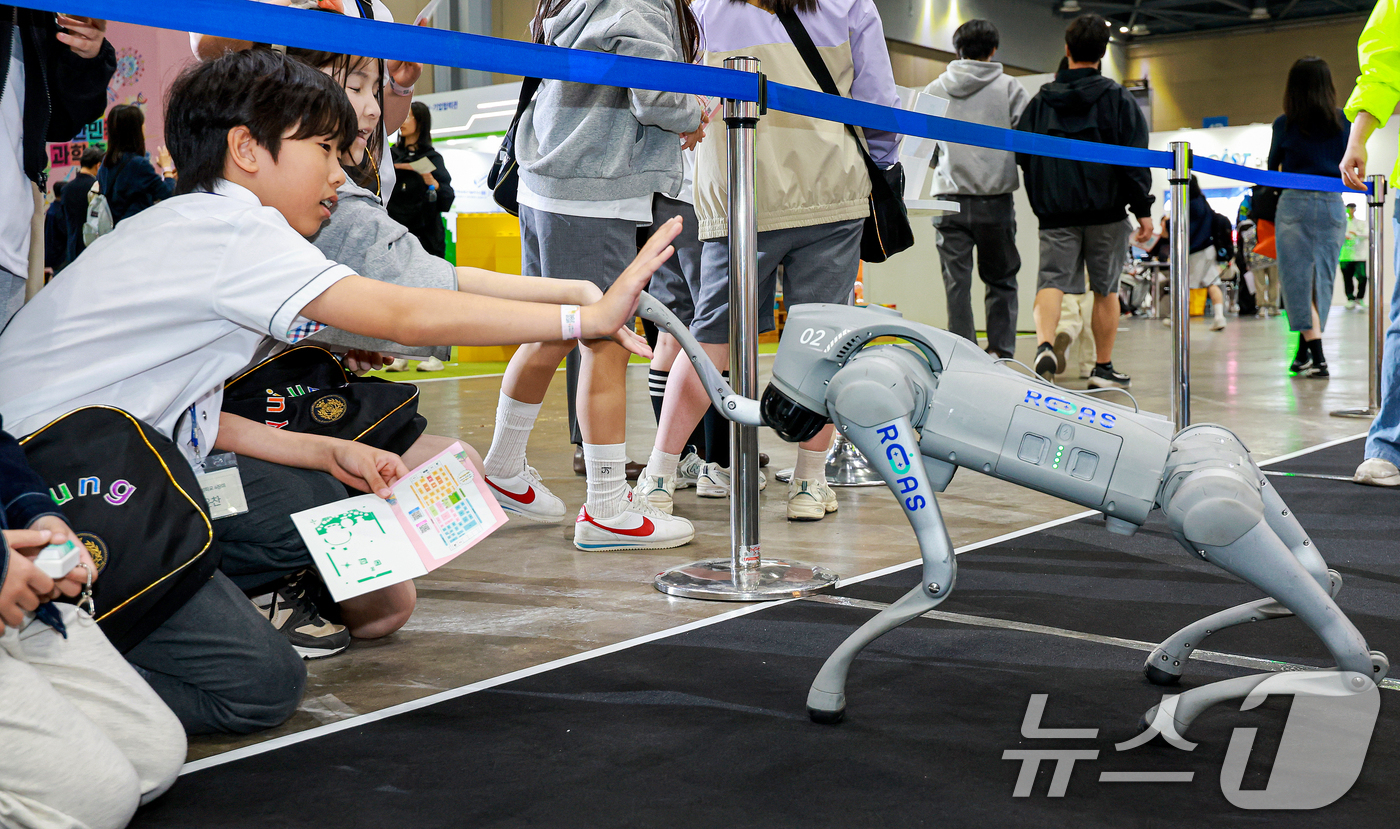 (고양=뉴스1) 이호윤 기자 = 24일 경기도 고양시 일산서구 킨텍스 제1전시장에서 열린 ‘2026 대한민국 과학축제 IN 경기’를 찾은 학생이 로봇 강아지와 손을 맞대고 있다.이 …