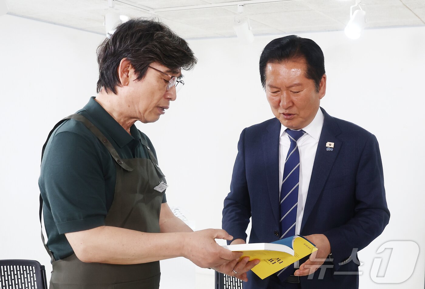 본문 이미지 - 지난해 4월 당시 정청래 더불어민주당 대표가 서울 성동구 언더스탠드에비뉴에 마련된 청각장애인 수제화 브랜드 '아지오' 매장 오픈 행사에 참석, 유시민 작가로부터 '사랑이 있으니 살아집디다' 책을 전달받고 있다. 2026.4.24 ⓒ 뉴스1 김민지 기자