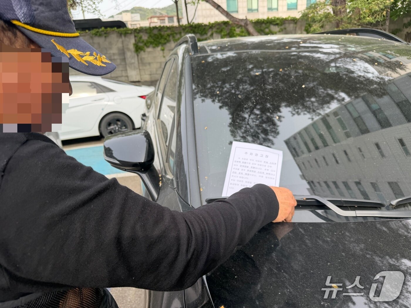 본문 이미지 - 충북 청주시 청원구의 한 공공기관 인근 아파트에서 경비원이 외부 차량에 주차 위반 안내문을 부착하고 있다. 2026.4.23/뉴스1 장예린 기자